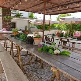 Rustic outdoor dining area with wooden tables, benches, and potted plants.