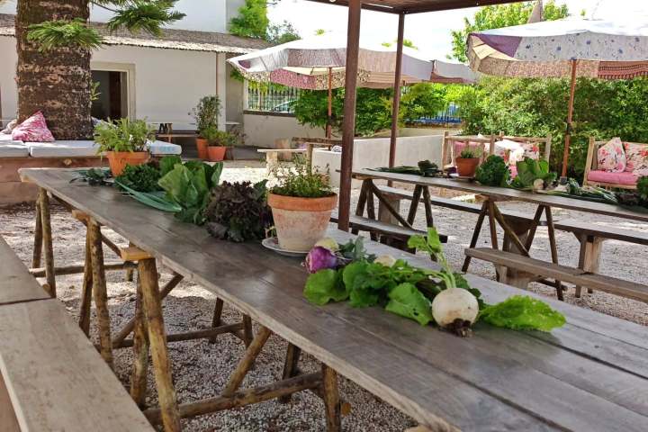 Rustic outdoor dining area with wooden tables, benches, and potted plants.