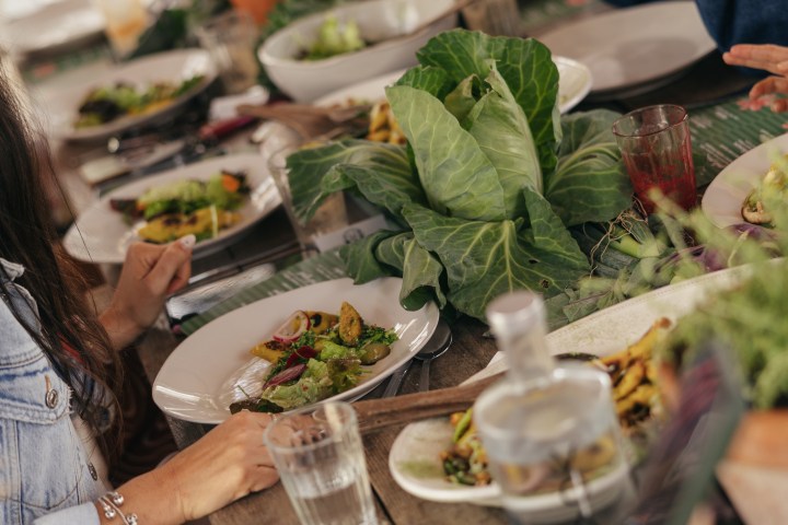 Group of people dining at a table with plates of salad and leafy greens.