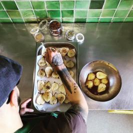Chef preparing baked pears with spices on a tray in a kitchen.