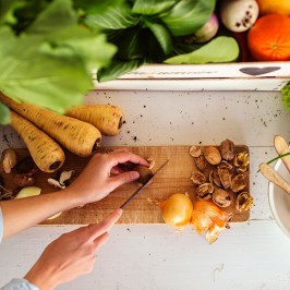 Person chopping vegetables on a cutting board surrounded by fresh produce.