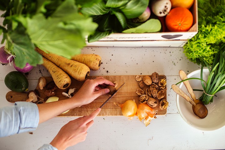 Person chopping vegetables on a cutting board surrounded by fresh produce.