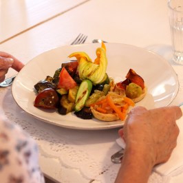 Person dining with a plate of mixed vegetables and a glass of water.