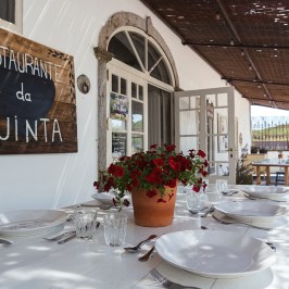 Outdoor dining table set at a restaurant patio with a flower centerpiece.