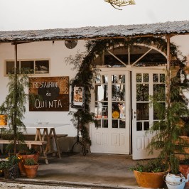 Charming outdoor restaurant entrance with wooden sign and greenery.