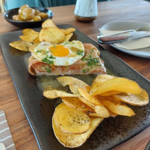 a sandwich sitting on top of a wooden table topped with plates of food