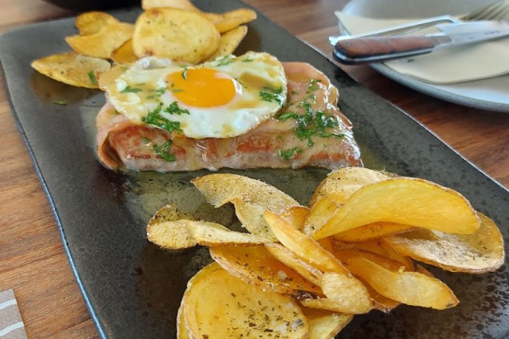 a sandwich sitting on top of a wooden table topped with plates of food
