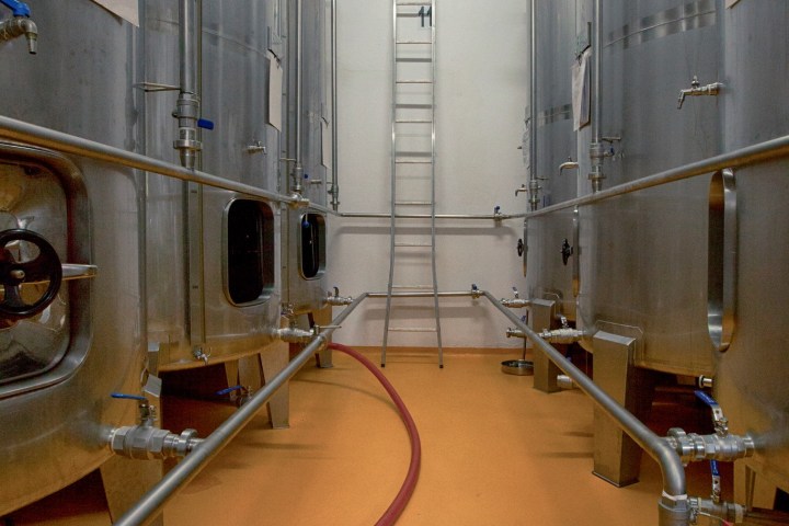 Industrial tanks in a brewery with pipes and a central ladder.