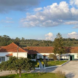 Rural house with red roofs, trees, and blue sky with clouds.