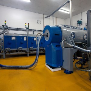 Industrial machinery with pipes in a factory setting, yellow floor.