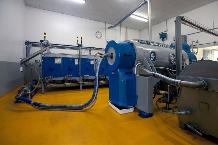 Industrial machinery with pipes in a factory setting, yellow floor.