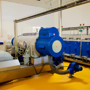 Industrial machinery in a factory with blue and gray equipment on a yellow floor.