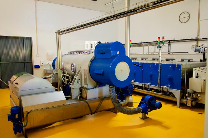 Industrial machinery in a factory with blue and gray equipment on a yellow floor.