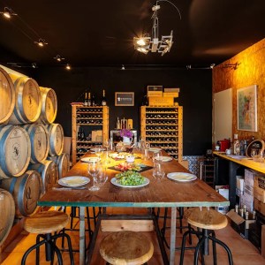 Cozy wine cellar with barrels, dining table, and wine racks.
