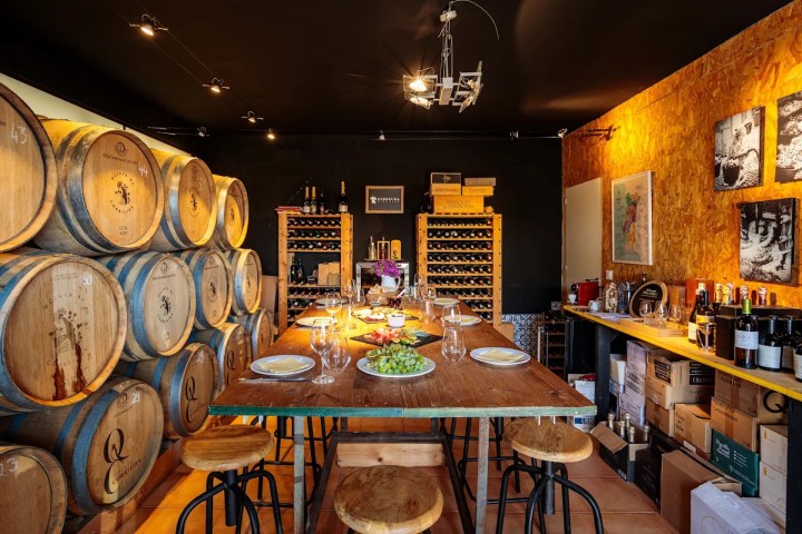 Cozy wine cellar with barrels, dining table, and wine racks.