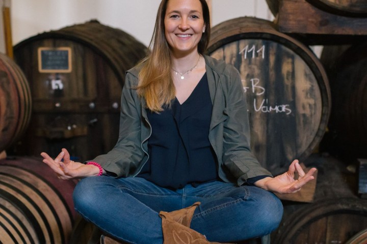 a woman sitting in front of a barrel