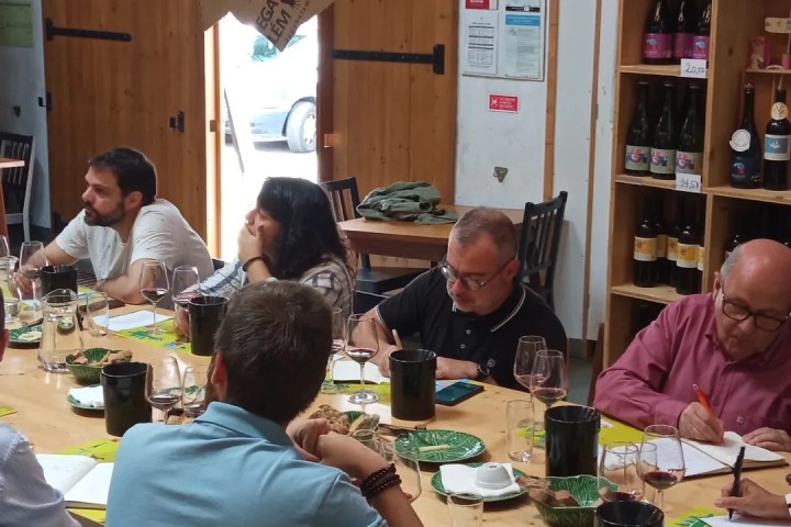People sitting around a table with wine glasses and notebooks in a cozy room.