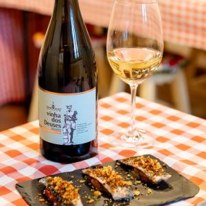 Wine bottle and glass with bite-sized dishes on a checkered tablecloth.