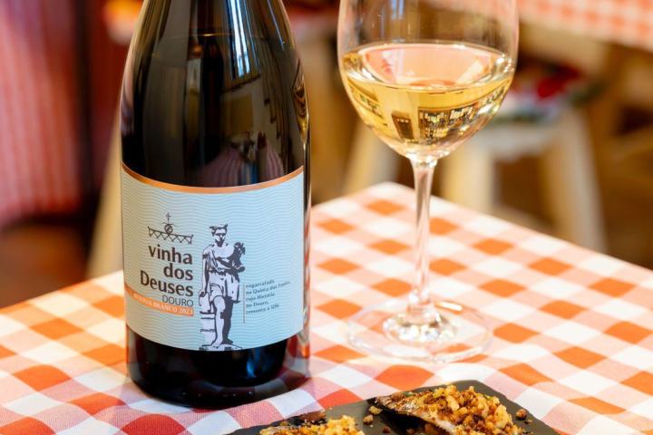 Wine bottle and glass with bite-sized dishes on a checkered tablecloth.