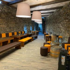 Cozy room with stone walls, wooden tables, barrel tables, orange-brown seating, and hanging lamps.