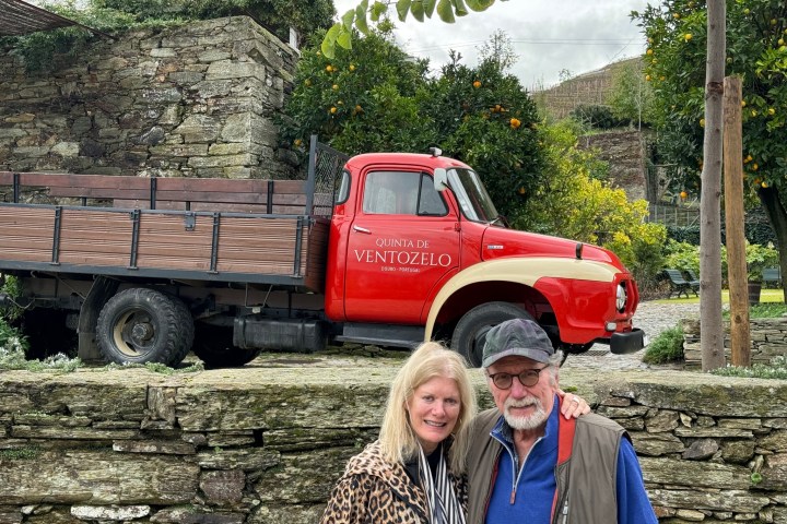 Two people smiling in front of a vintage red truck with 'Quinta de Ventozelo' on the side.