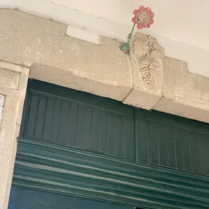 Green door with stone decoration and red valve above it.