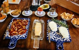 Cheese and charcuterie boards with breads and spreads on a wooden table.