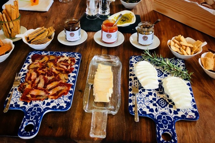 Cheese and charcuterie boards with breads and spreads on a wooden table.