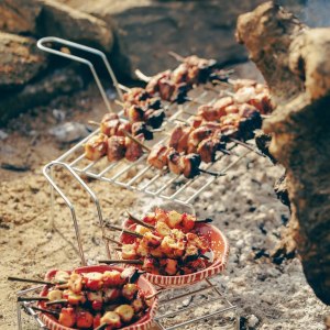 Skewers of meat and vegetables cooking on a metal grill over coals.