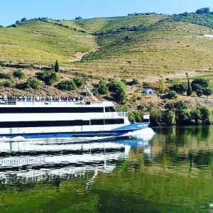 River cruise ship on a calm river with green hills in the background.