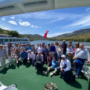 Group of people posing on a boat deck with scenic river background.