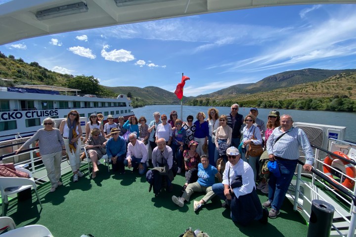 Group of people posing on a boat deck with scenic river background.