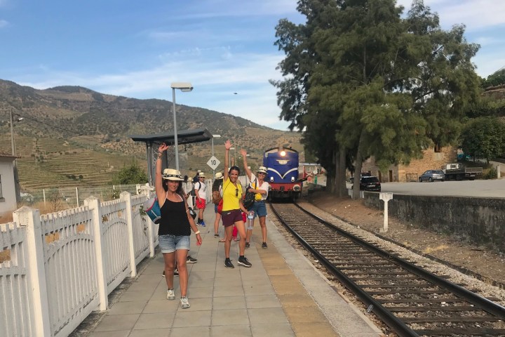 People walking on a train platform near tracks; train approaching.