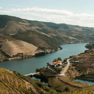 Scenic river winding through terraced hills and vineyards under a partly cloudy sky.