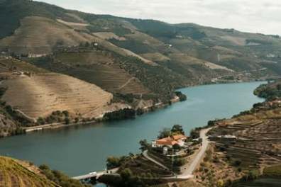 Scenic river winding through terraced hills and vineyards under a partly cloudy sky.
