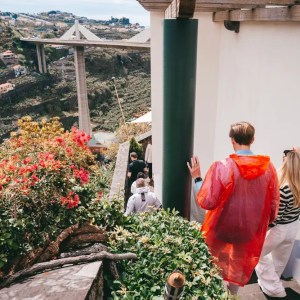 Tourists in bright clothes walking down outdoor stairs with a scenic view of a bridge and lush hillsides.