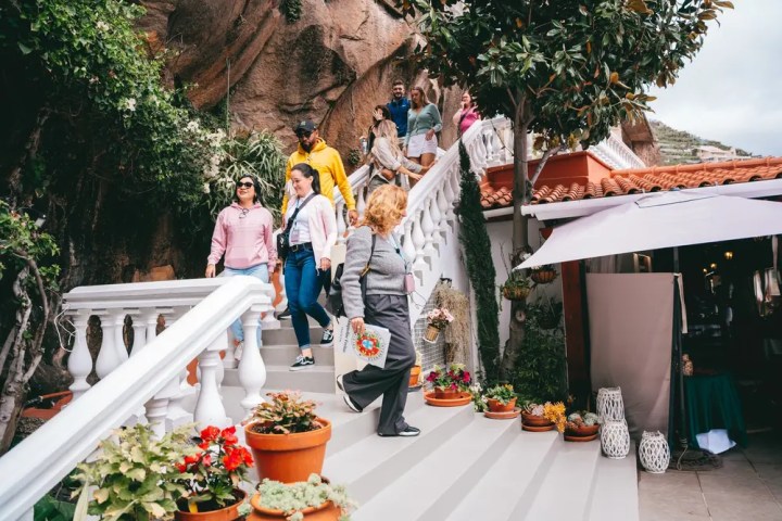 People walking down outdoor stairs near a building with plants in pots.