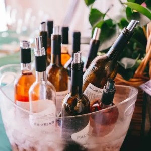 Wine bottles in an ice bucket with green plates in the background.