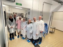 Group of people in protective clothing standing in a clean industrial setting.