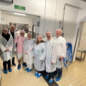 Group of people in protective clothing standing in a clean industrial setting.