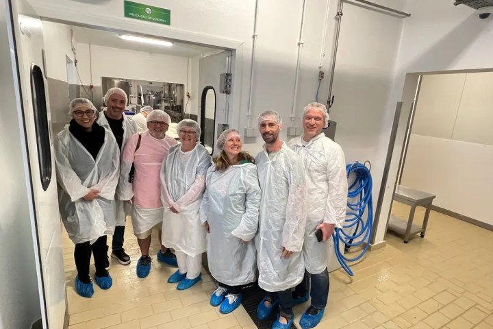 Group of people in protective clothing standing in a clean industrial setting.