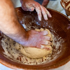 Hands kneading traditional bread dough in a clay bowl, Algarve