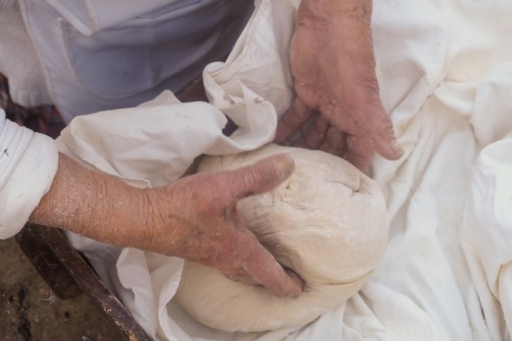 Hands kneading traditional bread dough in a clay bowl, Algarve