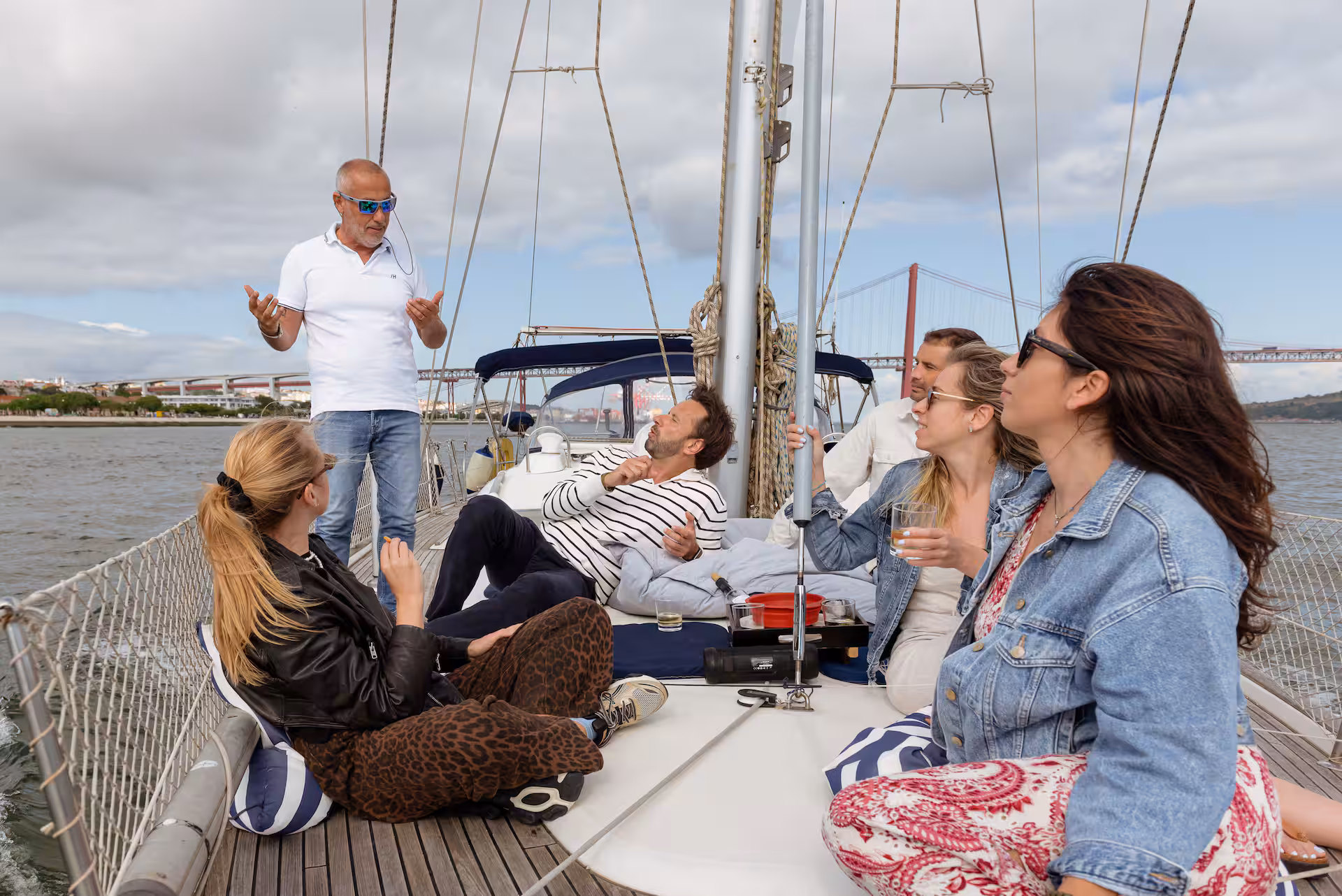 Small private group enjoying a guided wine tasting on board with Ponte 25 de Abril in the background