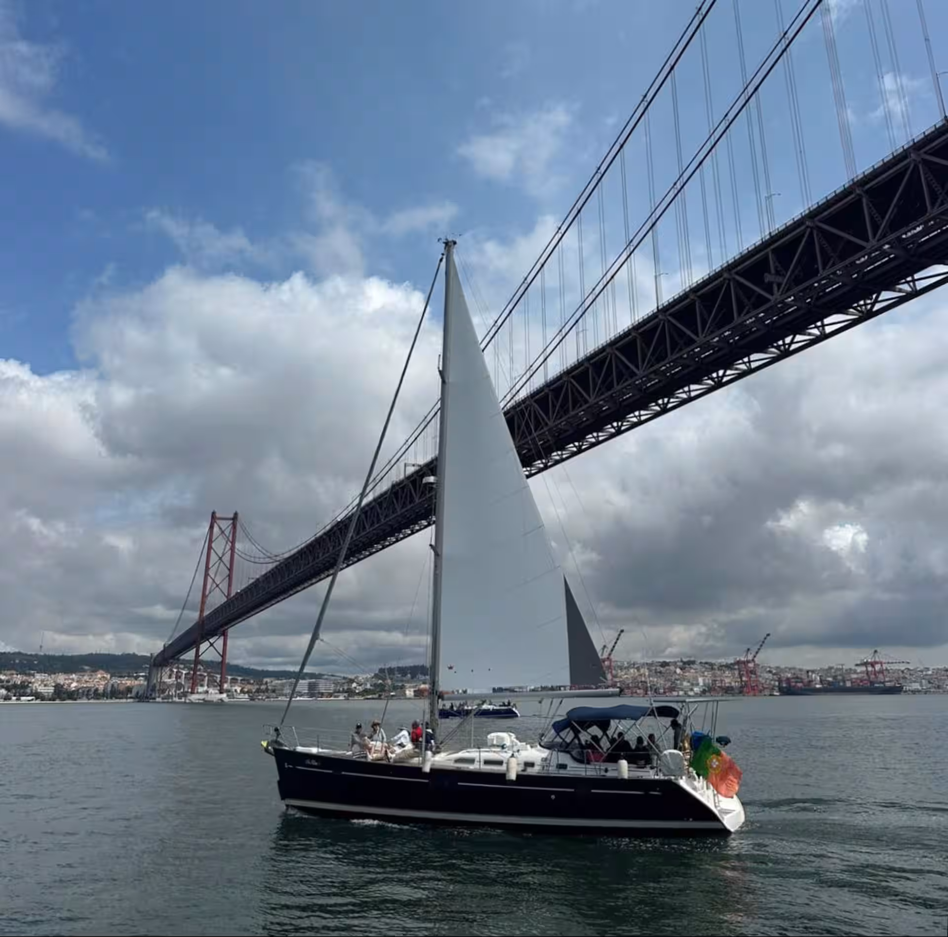 View of Cristo Rei and Ponte 25 de Abril from a private sailboat on the Tagus River in Lisbon