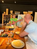 Two people at a table, one showing a map, surrounded by wine and food.