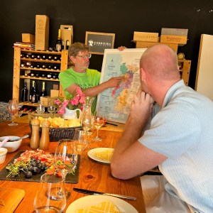 Two people at a table, one showing a map, surrounded by wine and food.
