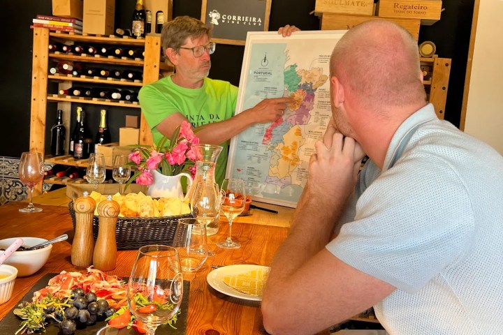 Two people at a table, one showing a map, surrounded by wine and food.