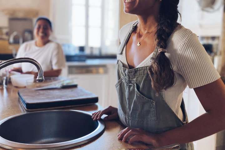Two women in a kitchen with a large salad on the counter.
