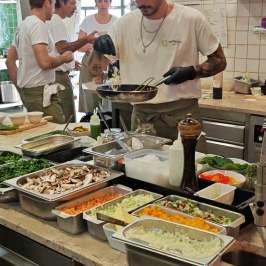 Chefs in a kitchen preparing food with fresh ingredients on counters.